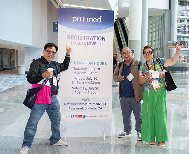 Pri-Med attendees with wayfinding sign in lobby